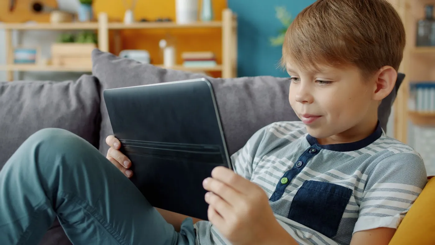 Chlapec sedí na gauči a hraje si na tabletu, ilustrace her zdarma pro děti